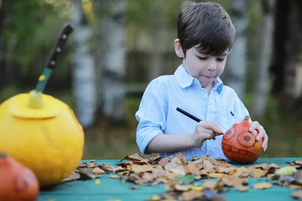 Autumn traditions and preparations for the holiday Halloween. A house in nature, a lamp made of pumpkins is cut out at the table.