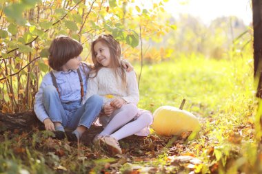 Genç bir aile güneşli bir günde sonbahar parkında yürüyüş yapıyor. Birlikte olmanın mutluluğu..