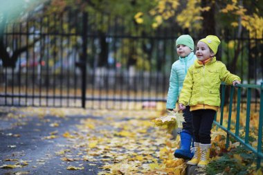 Çocuklar sonbahar parkında sonbaharda yürürler