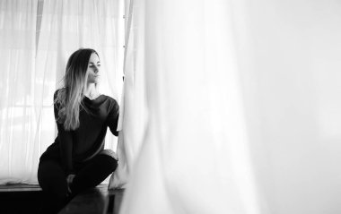 Genç bir kız büyük bir apartman dairesinde dinleniyor.