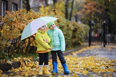 Çocuklar sonbahar parkında sonbaharda yürürler