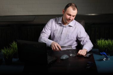 Adam masasında oturuyor ve bir lapto üzerinde çalışıyor.