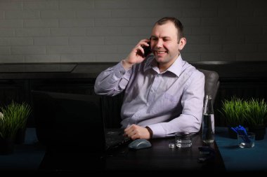 Adam masasında oturuyor ve bir lapto üzerinde çalışıyor.