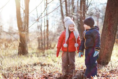 Çocuklar sonbahar parkında sonbaharda yürürler