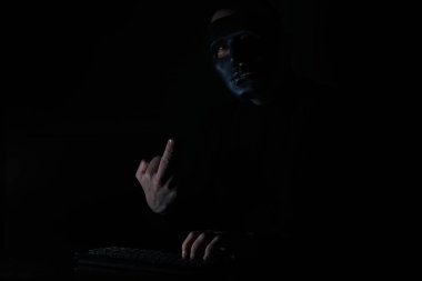 Dar bir masada maske takan bir adam klavyeye baskı yapıyor.