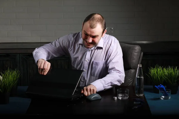 男は机の上に座ってノートパソコンを使って — ストック写真