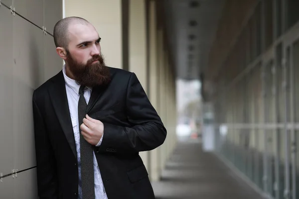 A bald bearded man in a suit and an umbrella cane on the stree