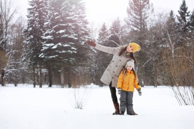 Mutlu bir aile kışın dışarıda karda oynar ve güler. Şehir parkı kış günü.
