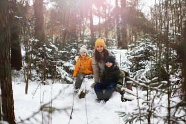 Mutlu bir aile kışın dışarıda karda oynar ve güler. Şehir parkı kış günü.
