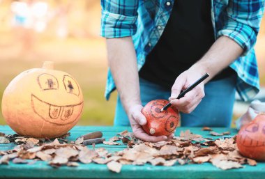 Sonbahar gelenekleri ve Cadılar Bayramı hazırlıkları. Doğada bir ev, masada balkabağından yapılmış bir lamba kesilir..