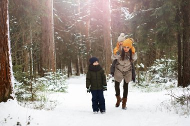 Mutlu bir aile kışın dışarıda karda oynar ve güler. Şehir parkı kış günü.