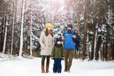 Mutlu bir aile kışın dışarıda karda oynar ve güler. Şehir parkı kış günü.