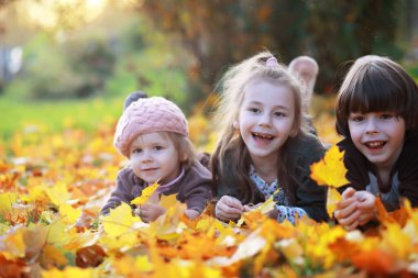 Genç bir aile güneşli bir günde sonbahar parkında yürüyüş yapıyor. Birlikte olmanın mutluluğu..