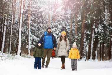 Mutlu bir aile kışın dışarıda karda oynar ve güler. Şehir parkı kış günü.