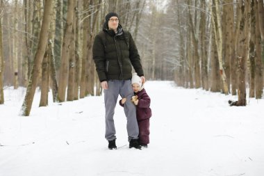 Mutlu bir aile kışın dışarıda karda oynar ve güler. Şehir parkı kış günü.