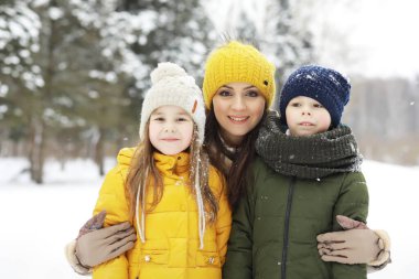 Mutlu bir aile kışın dışarıda karda oynar ve güler. Şehir parkı kış günü.