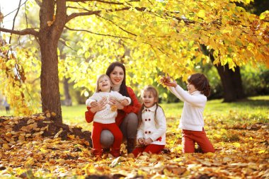 Genç bir aile güneşli bir günde sonbahar parkında yürüyüş yapıyor. Birlikte olmanın mutluluğu..