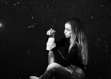 Genç kız siyah duvardaki bir şişeden süt içiyor.