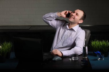 Adam masasında oturuyor ve bir lapto üzerinde çalışıyor.