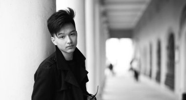 Kameraya poz veren Asyalı bir gencin siyah beyaz fotoğrafı.