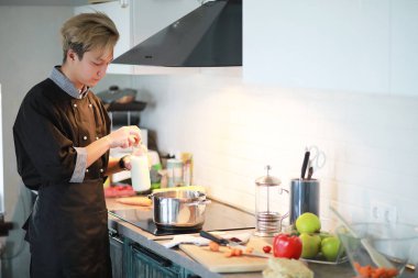 Genç bir Asyalı aşçı mutfakta yemek hazırlıyor.