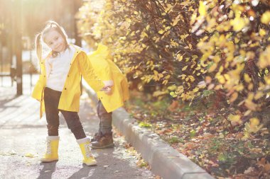 Çocuklar sonbahar parkında sonbaharda yürürler