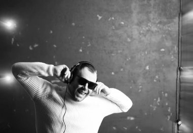 Beyaz kazaklı bir adam karanlık bir odada Musi dinliyor.