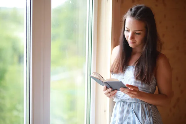 屋子窗户边的一个女孩正在看书 — 图库照片