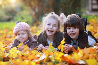 Genç bir aile güneşli bir günde sonbahar parkında yürüyüş yapıyor. Birlikte olmanın mutluluğu..