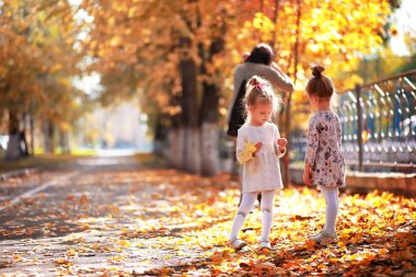 Yaprak parkta düşer. Sonbahar parkında yürüyüşe çıkmış çocuklar. - Aile. Düş! Mutluluk.