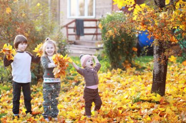 Genç bir aile güneşli bir günde sonbahar parkında yürüyüş yapıyor. Birlikte olmanın mutluluğu..