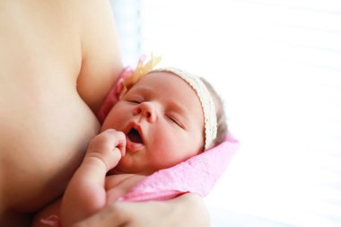 Yeni doğmuş bir bebek annesinin kollarında yatıyor. Avrupa görünümlü güzel bebek uyuyor.