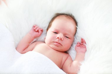 Yeni doğmuş bir bebek annesinin kollarında yatıyor. Avrupa görünümlü güzel bebek uyuyor.