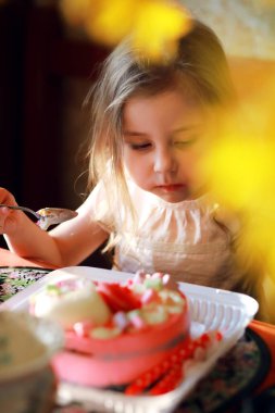 Çocuklar doğum gününü evde pasta ve balonlarla kutluyor.