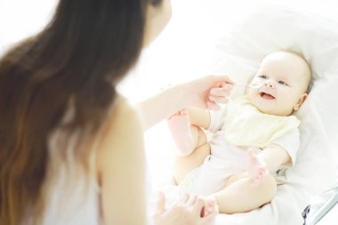 Annelik konsepti. Genç bir anne küçük bebeğini besler. İlk yem ve emzirme. Beyaz elbiseli büyük bir aile..