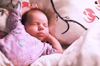 Yeni doğmuş bir bebek annesinin kollarında yatıyor. Avrupa görünümlü güzel bir bebek uyuyor..