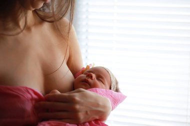 Yeni doğmuş bir bebek annesinin kollarında yatıyor. Avrupa görünümlü güzel bebek uyuyor.