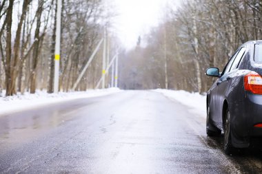 Modern SUV arabası kış yolunun kenarında duruyor. Kayak merkezine aile gezisi. Kış ya da bahar tatili macerası. Araba kışın karlı yolda dağlarda