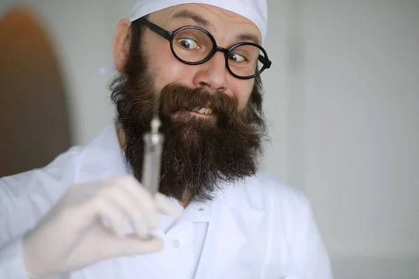 Doctor crazy. Mad beard scientist conducts experiments in a scientific laboratory. Performs research using syringe and a stethoscope.