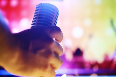 Arka planda arka ışıklandırmalı Retro tarzı mikrofon. Ses, müzik ve karaoke için klasik gümüş mikrofon. Konuşma yayın ekipmanı. Canlı pop, rock müzik performansı. Seçici odak