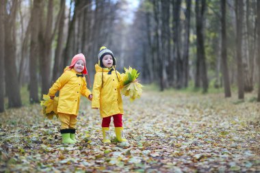 İznin sonbaharında küçük çocuklar sonbahar parkında yürüyor.