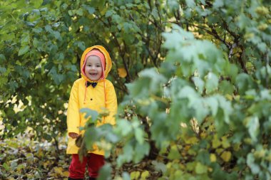 Sonbaharda dışarıda yürüyüş yapmak için yağmurluk giymiş bir çocuk.