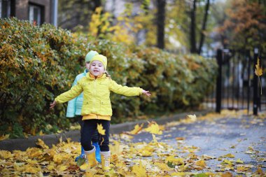 Çocuklar sonbahar parkında sonbaharda yürürler