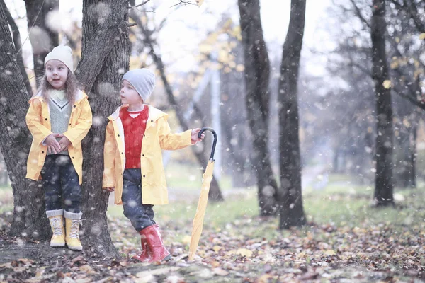 子供たちは最初の雪で公園を歩く — ストック写真