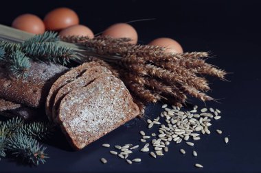 Siyah bir masada buğday ve glüten ile taze somun ekmek. Fırın ve market konsepti. Taze, sağlıklı çavdar ve beyaz somun ekmeği, çuval bezi üzerine serpiştirilmiş un. Tahıllı taze ev yapımı ekmek..