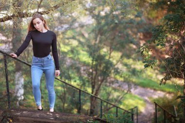 Sonbahar parkında yürüyüş yapan genç ve güzel bir kız. Şehir parkında yapraklar dökülüyor. Ekim.