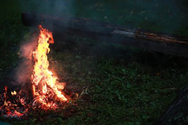Büyük ateşte yanan kızıl kıvılcımlar uçuşur. Yanan kömürler, yanan parçacıklar siyah arkaplanda uçuşuyor..