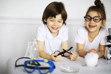 Kimya dersindeki iki tatlı çocuk beyaz arka grubunda deneyler yapıyor.