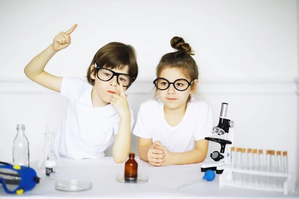 在化学课上两个可爱的孩子在白色背景上进行了分离实验 — 图库照片