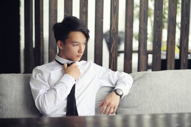 Genç bir Asyalı işadamı bir kafede ortak bekliyor. Bir kafede Koreli genç bir adam telefonda konuşuyor.